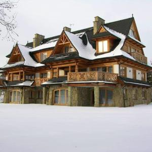 een groot houten huis met sneeuw op het dak bij 2 bedrooms appartement with enclosed garden and wifi at Koscielisko in Kościelisko