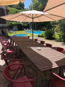 a long wooden table with chairs and an umbrella at Quinta Casa da Fonte in Vieira do Minho