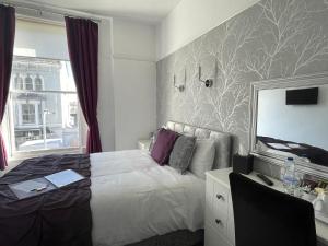 a bedroom with a white bed and a mirror at Lynton House in Llandudno