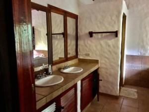 a bathroom with two sinks and a large mirror at Villas la Foresta in Manuel Antonio