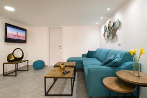 een woonkamer met een blauwe bank en 2 tafels bij Apartment with jacuzzi & pool table, Haifa center close to Bahai Garden in Haifa