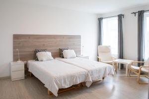 a white bedroom with a large bed and chairs at Old Town apartments/Senamiesčio apartamentai in Ukmergė