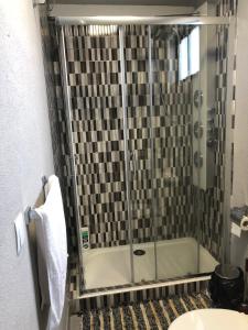 La salle de bains est pourvue d'une douche avec une porte en verre. dans l'établissement Ndussole House, à Talatona