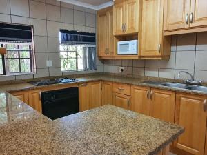 a kitchen with wooden cabinets and a granite counter top at Tamboti House in Malelane