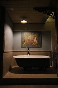 a bath tub in a bathroom with a painting on the wall at Artists Residence in Tbilisi in Tbilisi City