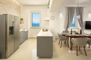 a kitchen and dining room with a table and a refrigerator at SEAFRONT NORTH HOUSE SUTIVAN - new luxury three-bedroom villa - unforgettable panoramic views of the sea - roof terrace with jacuzzi - first row next to the beach and right next to all facilities - secured parking in Sutivan