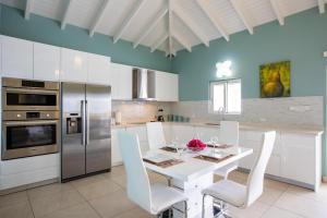 a kitchen with a white table and white chairs at Reflection Y 5 Star Villa in Maho Reef