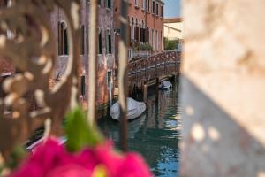 un canal avec un pont et un bateau dans l'eau dans l'établissement COLOMBINA HOME Venice with canal view, à Venise
