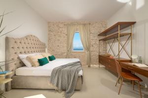a bedroom with a bed and a desk and a window at SEAFRONT NORTH HOUSE SUTIVAN - new luxury three-bedroom villa - unforgettable panoramic views of the sea - roof terrace with jacuzzi - first row next to the beach and right next to all facilities - secured parking in Sutivan