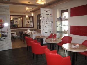 Riviéra Rooms Vendégszobák في موسونماجياروفار: مطعم فيه كراسي حمراء وطاولات في الغرفة