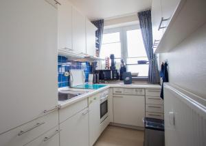 uma cozinha com armários brancos, um lavatório e uma janela em Appartement - Weltringpark 2-D Winterberg em Winterberg