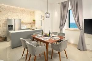 a kitchen and dining room with a wooden table and chairs at SEAFRONT NORTH HOUSE SUTIVAN - new luxury three-bedroom villa - unforgettable panoramic views of the sea - roof terrace with jacuzzi - first row next to the beach and right next to all facilities - secured parking in Sutivan