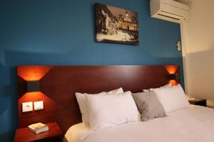 1 dormitorio con 1 cama con pared azul en Initial by Balladins Lyon Villefranche-sur-Saône, en Villefranche-sur-Saône