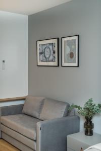 a couch in a living room with two pictures on the wall at River city apartments No 3 by URBAN RENT in Kaunas