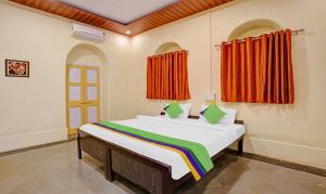 马泰兰Treebo Cecil Resort, 600 Mtrs From Matheran Railway Station的一间卧室配有带橙色窗帘的大床 更多37张照片