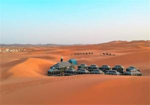 a group of domed buildings in the desert at Desert Life Camp in Merzouga