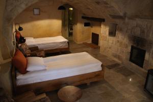 two beds in a room with a stone wall at 1811 Cave Hotel in Nevsehir