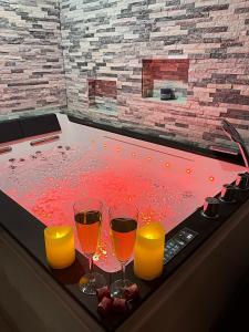 Superbe appartement privé avec jacuzzi في Saint Etienne: كأسين من النبيذ وشموع في حوض استحمام ساخن