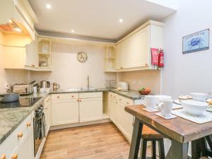 a kitchen with white cabinets and a wooden table at Melanie's Cottage in Weymouth
