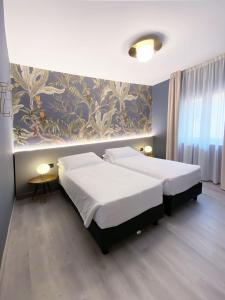 a bedroom with two beds and a wall with a mural at Hotel Astoria in Garda