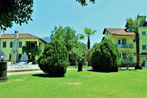 a house with two bushes in front of a yard at Summer Life Villa Apart in Dalyan