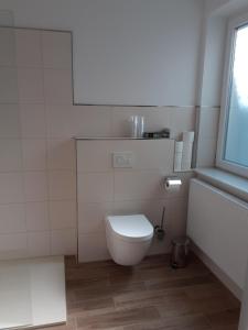 a white bathroom with a toilet and a window at Ferienwohnung Krabbe in Wilhelmshaven