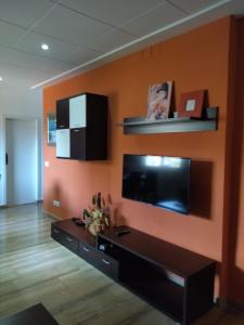 トッサ・デ・マールにあるApartment Tossa Villageのオレンジ色の壁のリビングルーム(薄型テレビ付)
