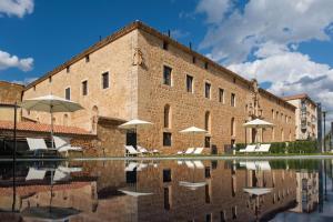 um edifício com cadeiras e guarda-sóis ao lado de uma piscina em Castilla Termal Burgo de Osma em El Burgo de Osma