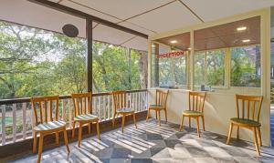 马泰兰Treebo Cecil Resort, 600 Mtrs From Matheran Railway Station的阳台的门廊配有椅子和桌子