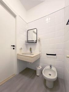 a white bathroom with a sink and a toilet at Hotel Astoria in Garda