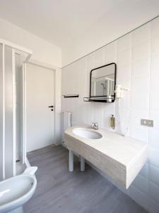 bagno bianco con lavandino e specchio di Hotel Astoria a Garda