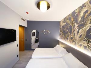 a bedroom with two beds and a wall with a painting at Hotel Astoria in Garda