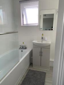 a white bathroom with a tub and a sink at Modern 2 Bed Chalet - 27 Bermuda Holiday Park in Hemsby