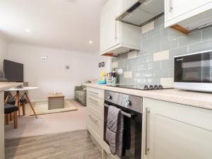 a kitchen with white cabinets and a stove top oven at Lighthouse Lofts - Longships in Camborne