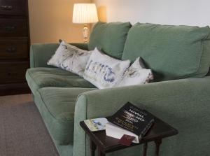 a green couch with pillows and a book on a table at Mallard Grange B&B in Ripon