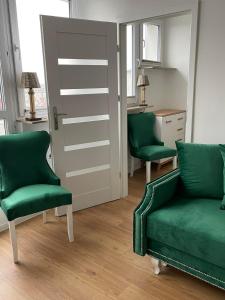 シュチェチンにあるMieszkanie Centrumのリビングルーム(緑の椅子2脚、ドア付)