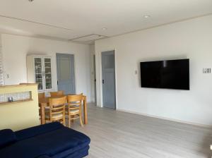 ein Wohnzimmer mit einem Sofa und einem TV an der Wand in der Unterkunft Holiday Villa 旅生 in Tonosho
