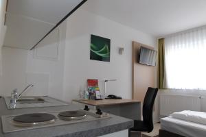 a kitchen with a sink and a stove in a room at Hotel Rappensberger in Ingolstadt