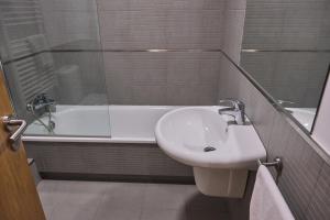 ein Badezimmer mit einem Waschbecken und einer Badewanne mit einem Waschbecken in der Unterkunft Pensión A Solaina 2 in O Pino 