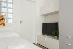 a white bedroom with a bed and a tv at SkyView Nolo Studio Via Varanini in Milan