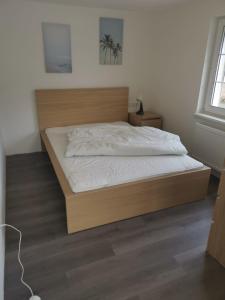 1 cama con marco de madera en un dormitorio en Ferienhaus KaTi Whg1, en Knüllwald