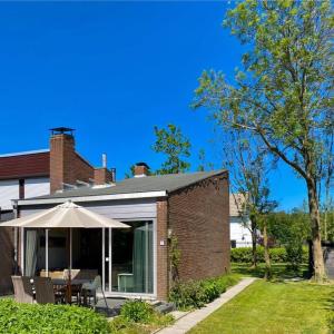 uma casa de tijolos com um guarda-chuva e um pátio em Holidayhouse - Lepelblad 7 Nieuwvliet-Bad em Nieuwvliet