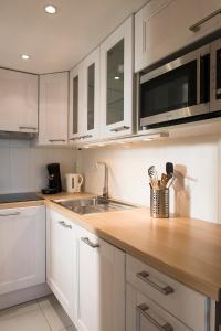 a kitchen with white cabinets and a wooden counter top at L'Aigrette - Front de mer-Accès direct plage in Leucate
