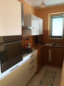 una cucina con armadi bianchi e piano cottura di B&B Villa zia Febronia a Patti