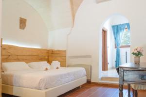 a bedroom with a bed and a table and a window at Masseria Le Lamie in Villa Castelli