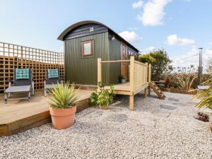 a tiny house with a deck and a chair at Badgers Rest in Tintagel