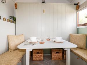 uma mesa branca num quarto com duas cadeiras e uma mesa com copos em Badgers Rest em Tintagel