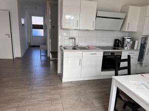 a kitchen with white cabinets and a wooden floor at Ostfrieslands Perle Ferienwohnung an der Nordseeküste, Sauna, Terrasse, Garten, ruhige Lage, WLAN in Norden