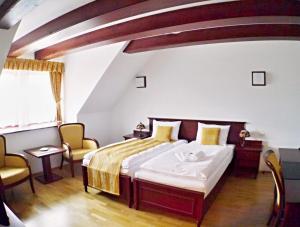 a bedroom with a bed and two chairs at Hradná stráž Hotel&Apartments s privátnym wellness in Topoľčianky