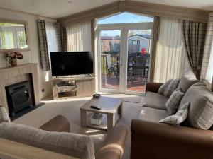 a living room with a couch and a television at Beautiful 2 bedroom Helmsley Lodge in Northampton